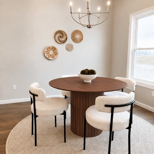 Cove Round in the walnut finish — round fluted pedestal table with four black-frame bouclé chairs in a dining room